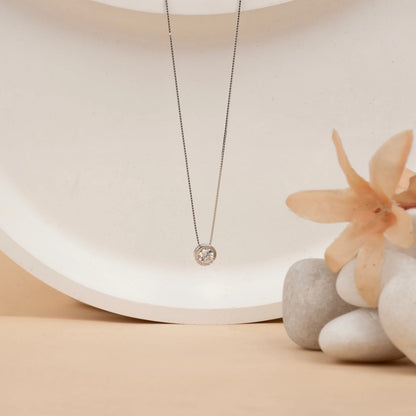 Delicate silver necklace with a round pendant on a neutral background