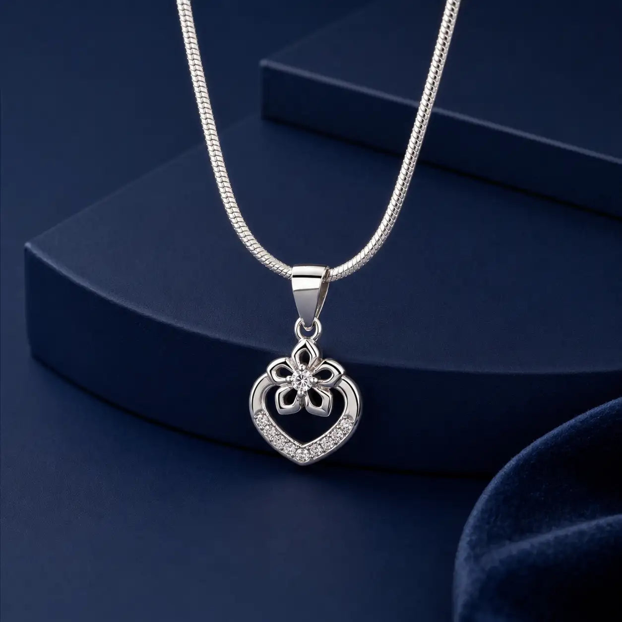 Silver heart-shaped pendant necklace with a floral design and embedded crystals.