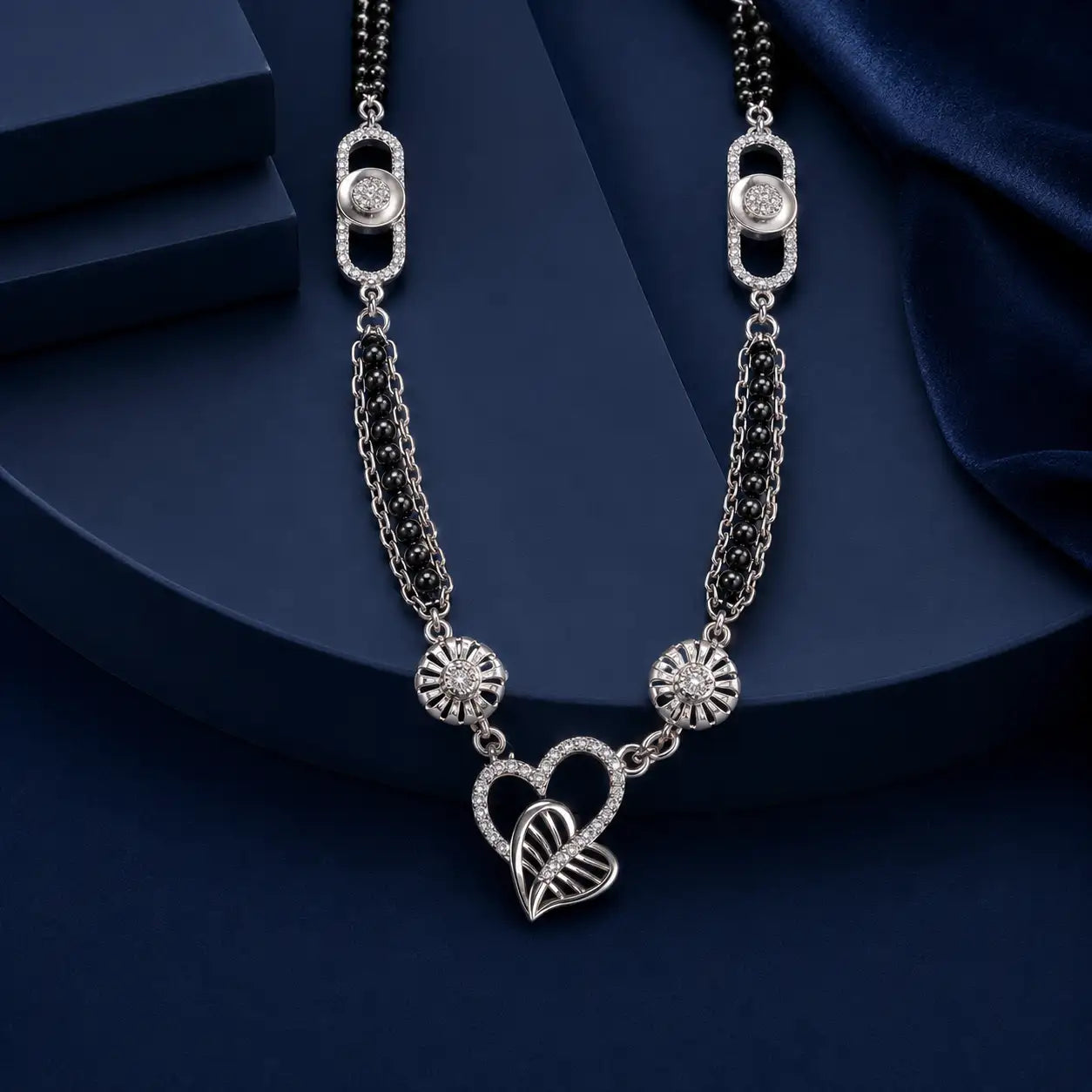 Silver heart-shaped pendant necklace with intricate detailing and embedded diamonds, featuring a central double-heart design flanked by sunburst motifs.