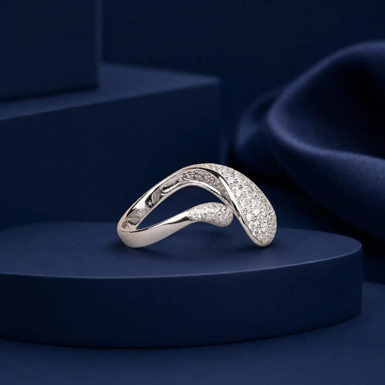 A sleek, silver-toned ring with a flowing, curved design and pavé-set diamonds.